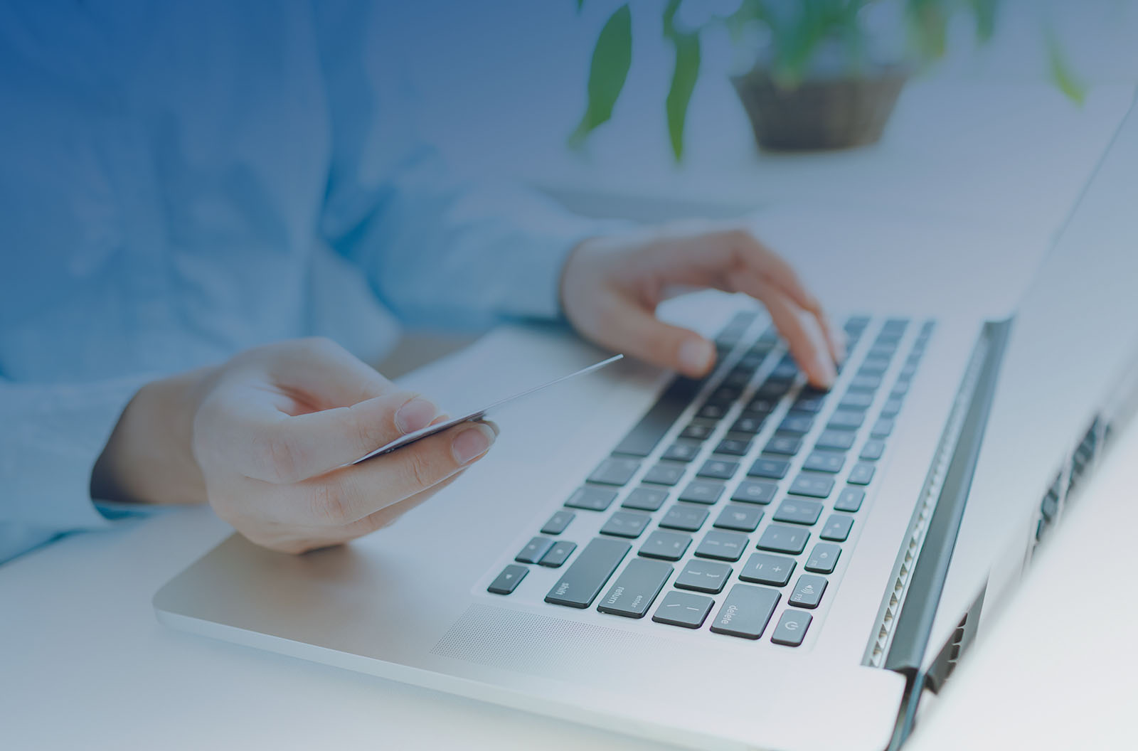 Person holding a credit card over a laptop